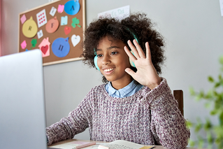 child raising hand in front of computer