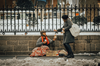 woman donating to homeless man