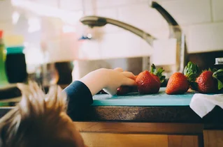 child reaching for strawberry